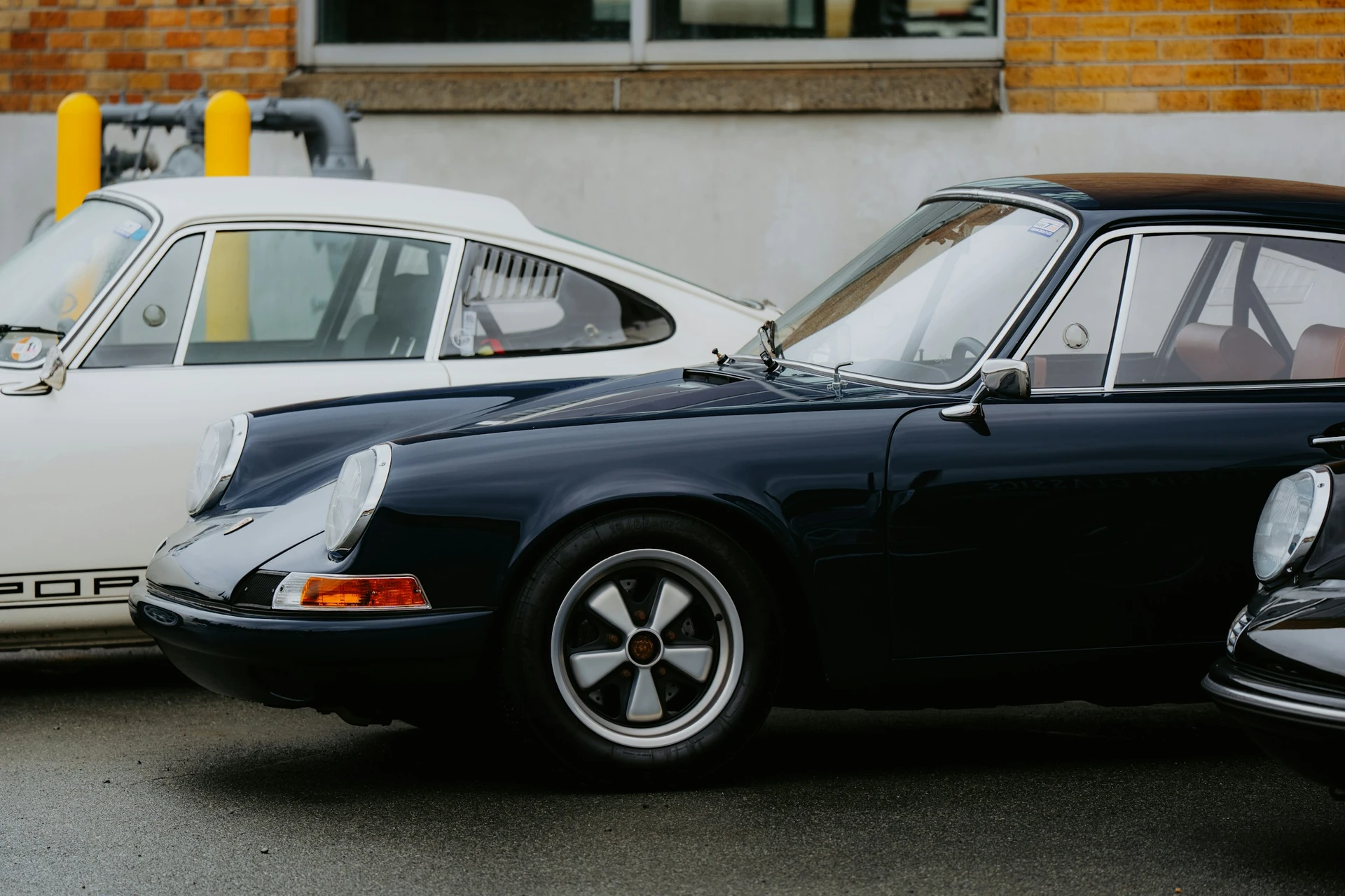 Porsche 911 clásicos negros y marfil aparcados juntos