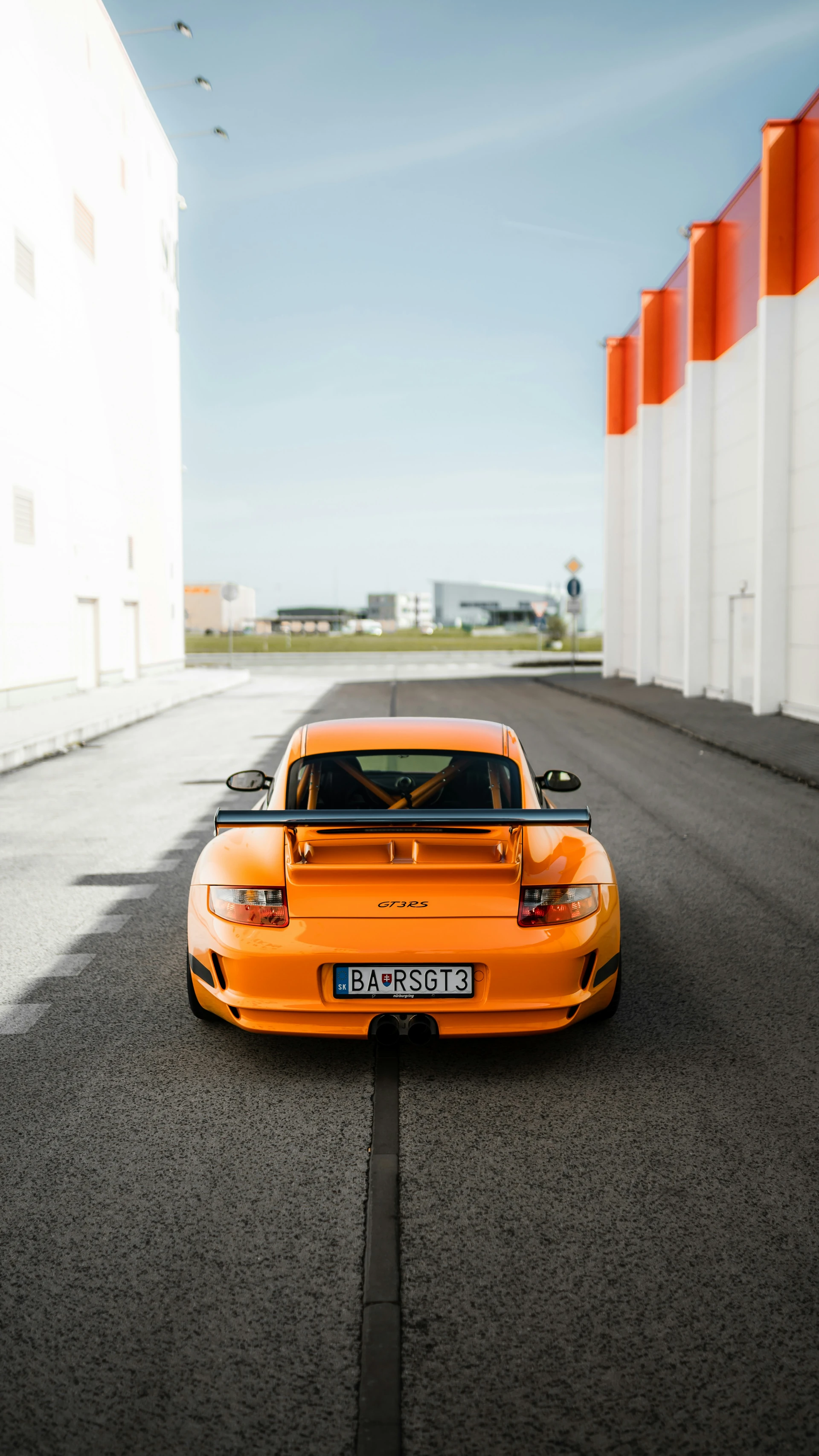 Trasera de un Porsche 911 GT3 RS naranja con el alerón y la jaula de seguridad visibles