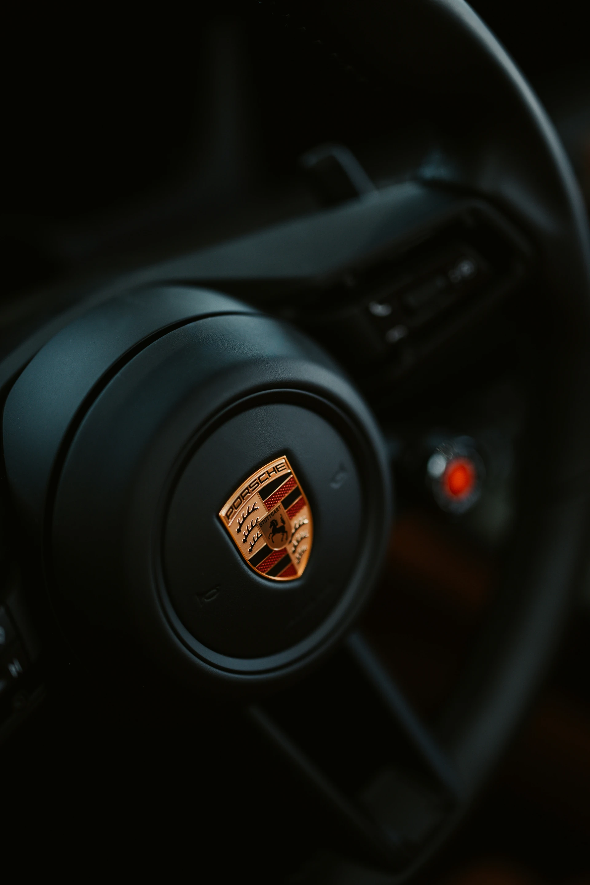 Primer plano del escudo Porsche, el cuero y los mandos de un volante moderno