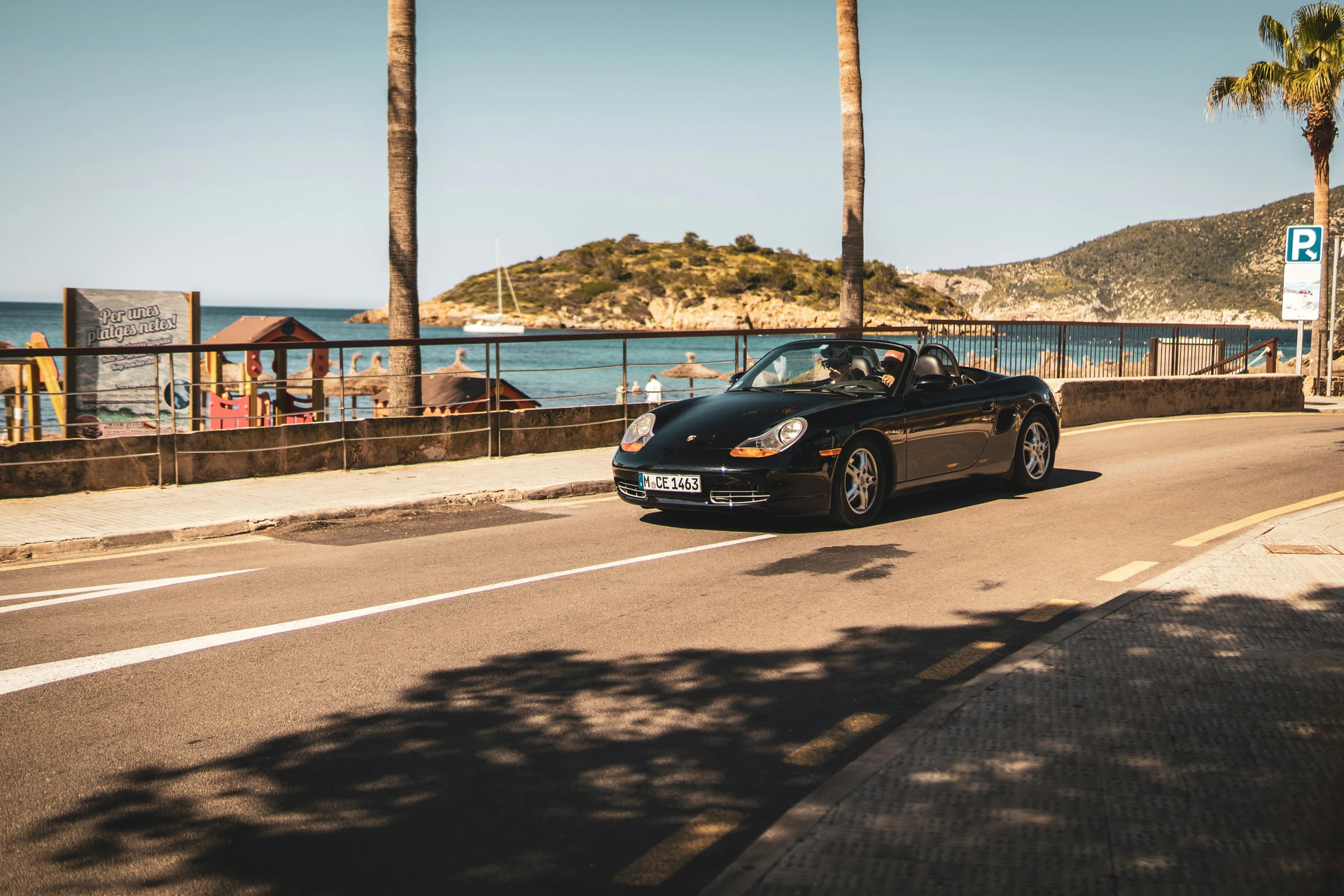 Porsche Boxster negro por una carretera costera de Mallorca bajo el sol