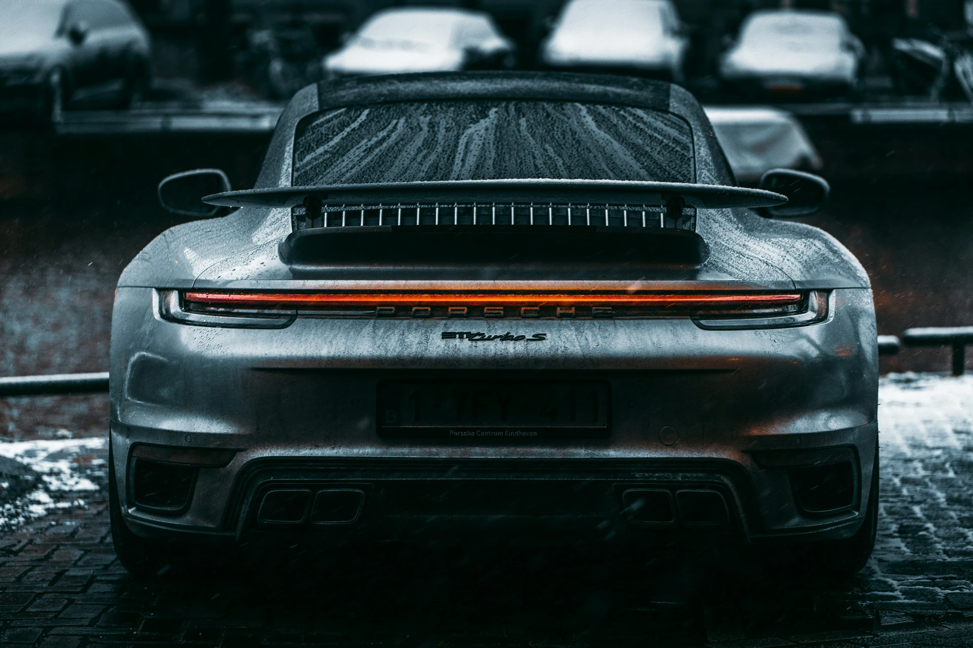 Trasera de un Porsche 911 Turbo S plateado cubierta de gotas de lluvia en Ámsterdam